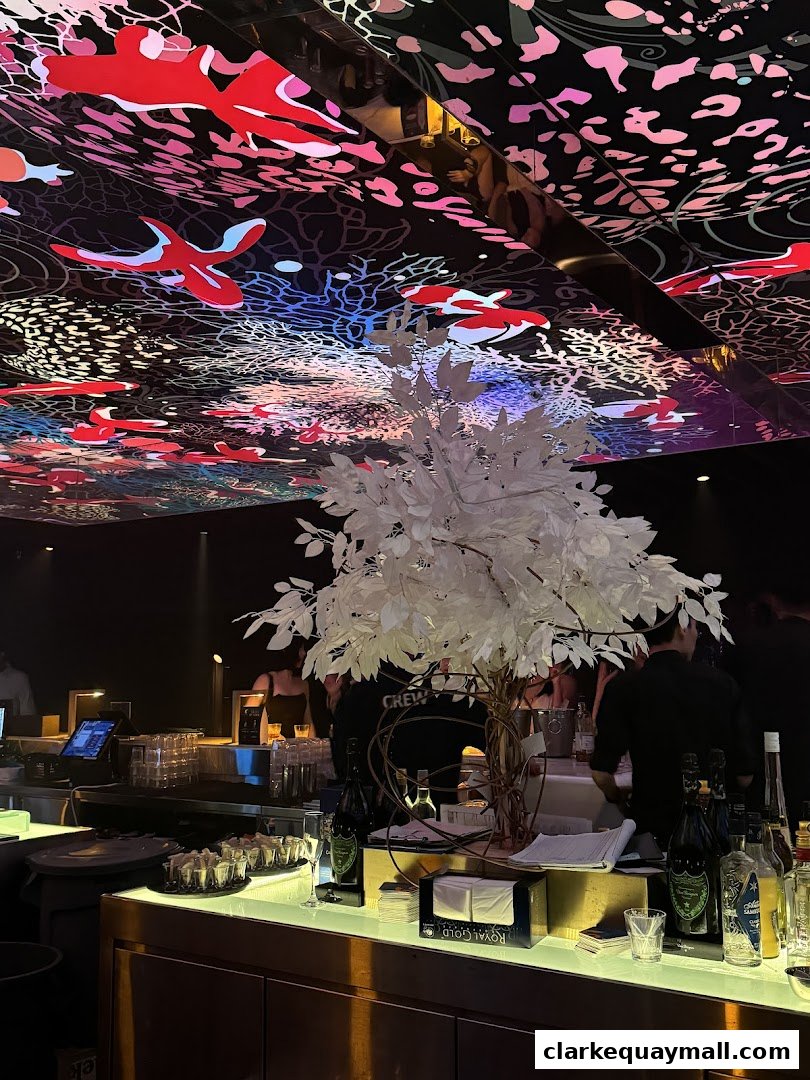 A bar area with bottles, glasses, and a decorative tree under a vibrant, patterned ceiling.