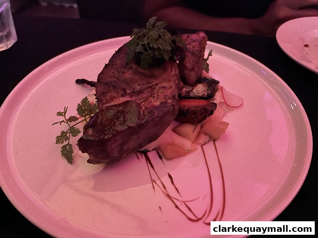A beautifully plated dish featuring a thick cut of meat with roasted vegetables and a garnish.