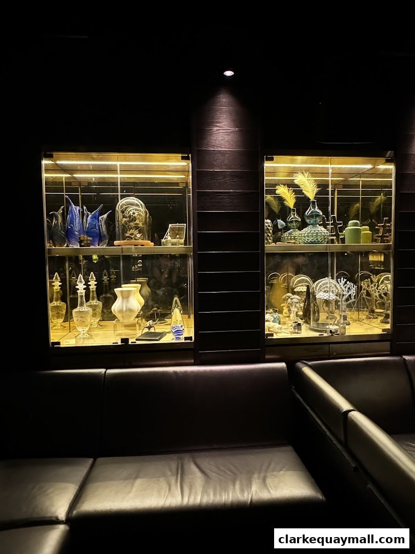 Two illuminated display cabinets filled with decorative items above dark leather seating.