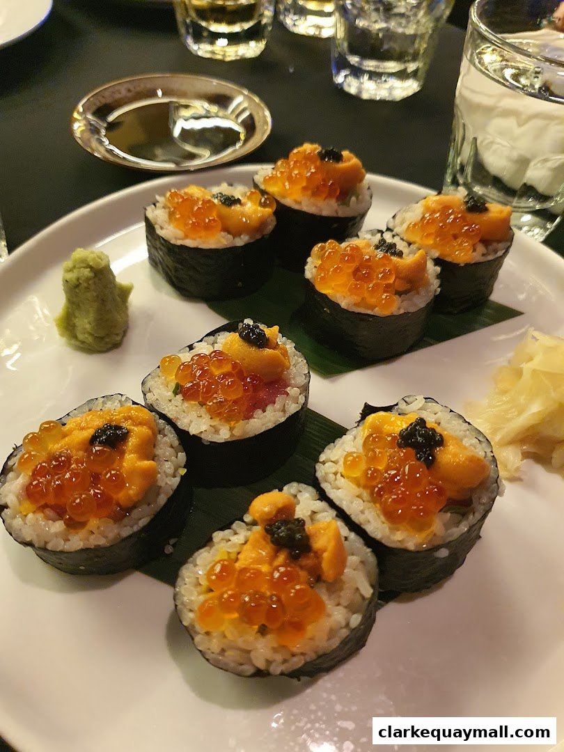 A plate of sushi rolls topped with uni, ikura, and caviar, served with wasabi and pickled ginger.