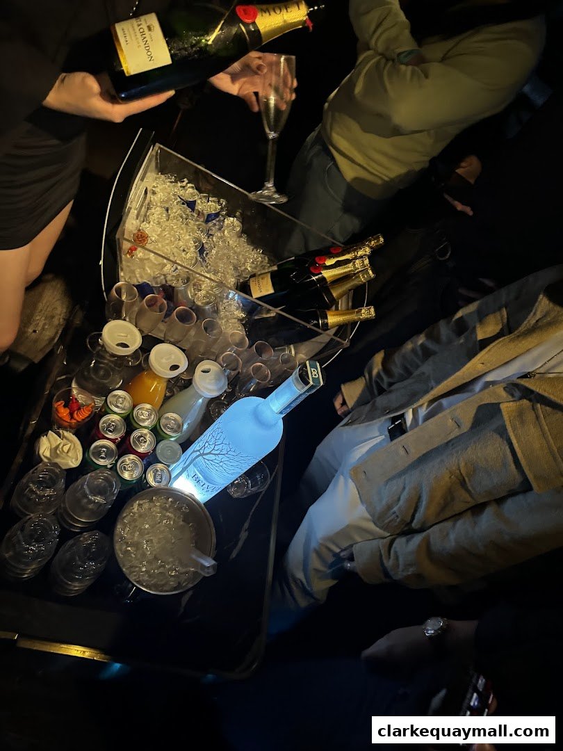People enjoying champagne and vodka with mixers at a table in a dimly lit venue.