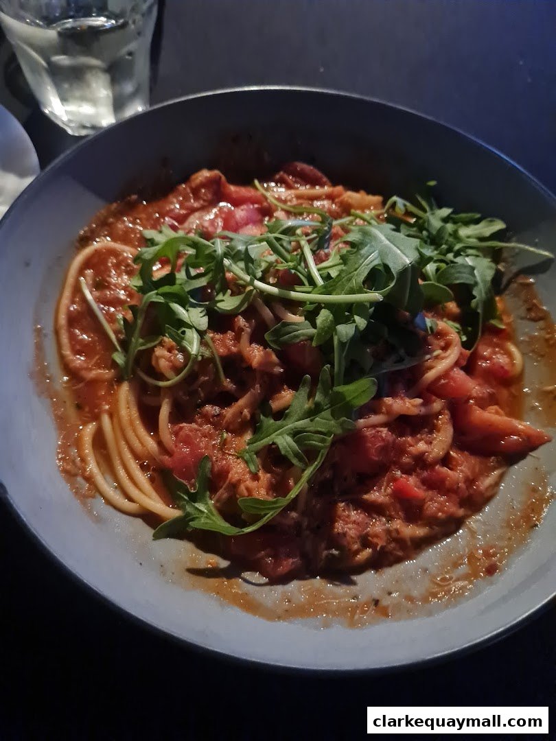 A close-up shot of a pasta dish with tomato sauce and arugula.