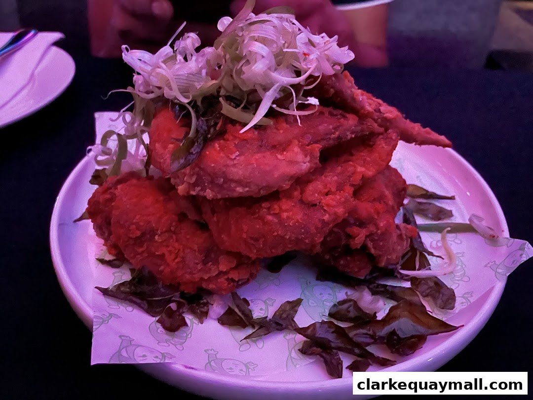 A plate of crispy fried chicken wings topped with shredded scallions and herbs.