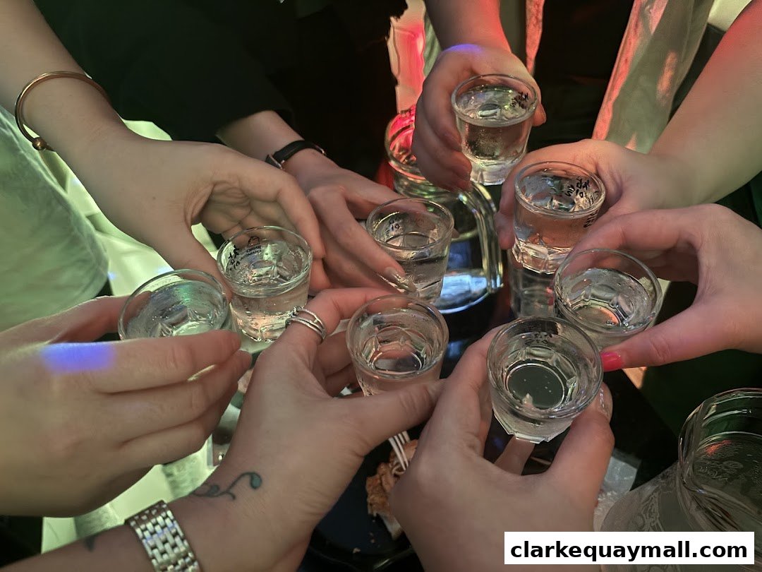 A group of people clinking shot glasses filled with clear liquid.