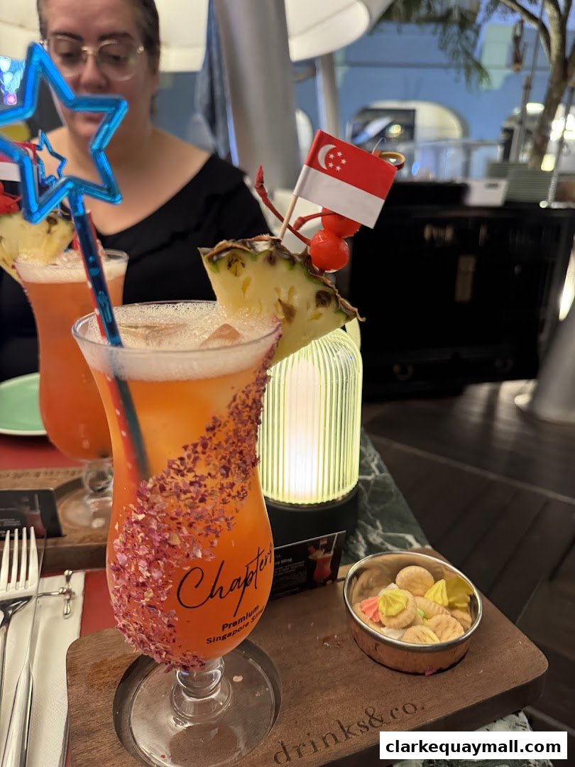 A person enjoys a tropical cocktail garnished with pineapple and a Singapore flag.