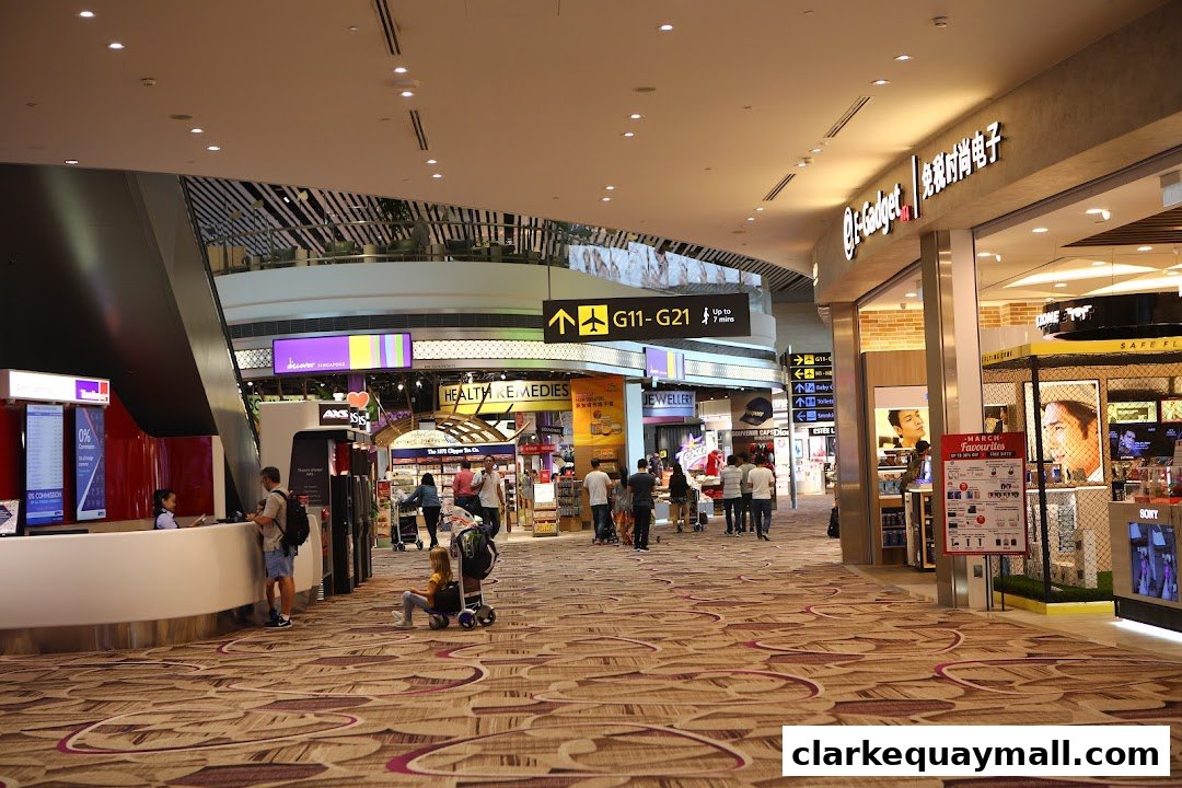 A busy airport concourse with various shops and directional signage.