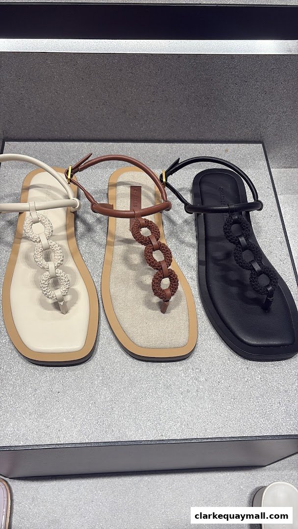Three pairs of stylish flat sandals in white, brown, and black with decorative chain detailing.
