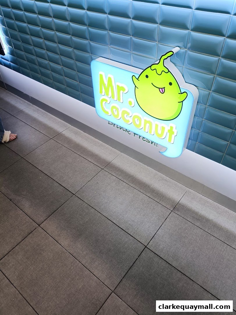 A glowing sign for 'Mr. Coconut' with a cute coconut character and the slogan 'DRINK FRESH!'