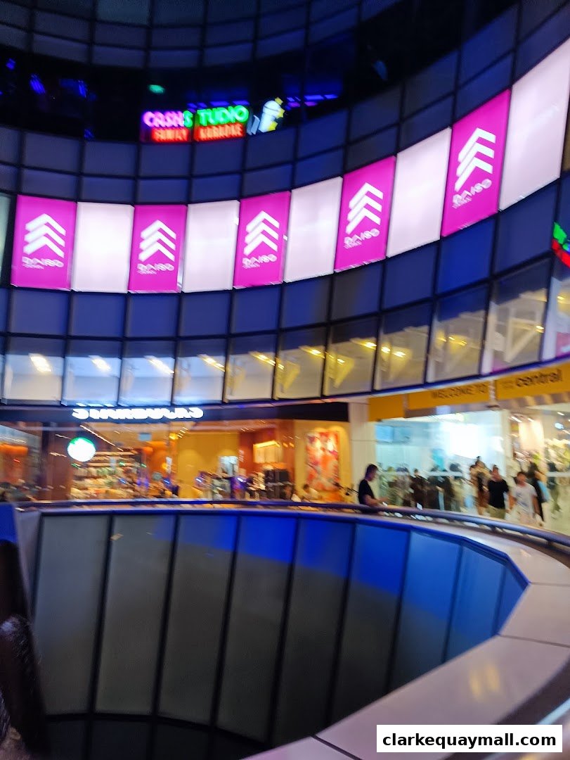Interior view of a shopping mall with various shops and escalators visible.