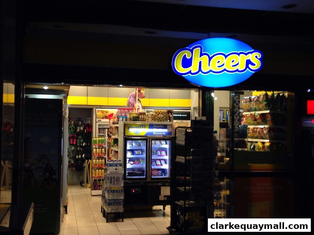 The brightly lit entrance of Cheers convenience store at night, showcasing snacks and drinks.