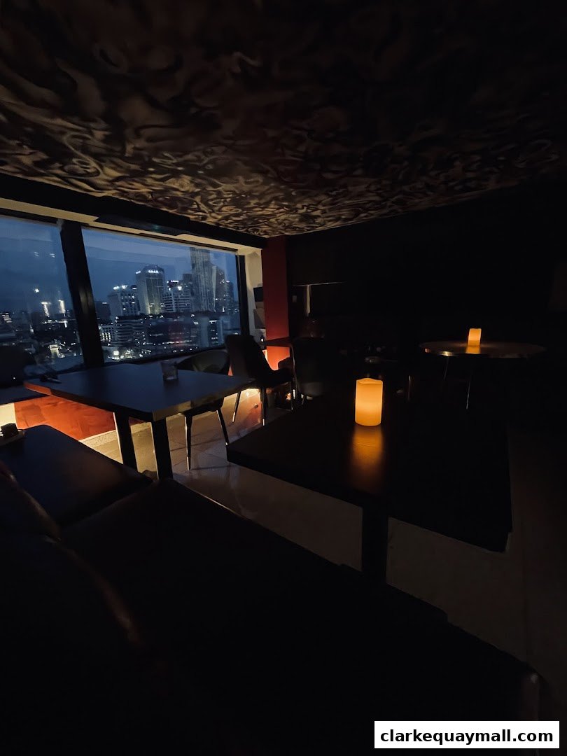 Interior of a dimly lit lounge with city views and candlelit tables.
