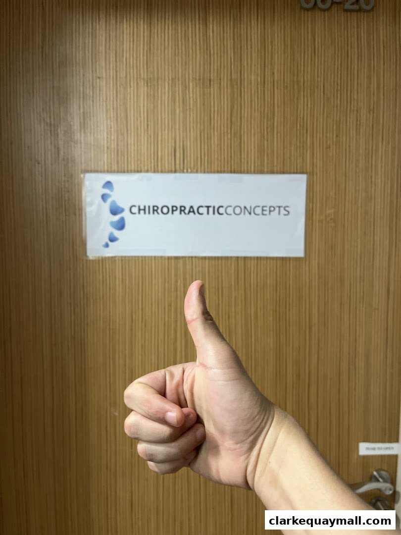 A hand gives a thumbs up in front of a door with the Chiropractic Concepts logo.