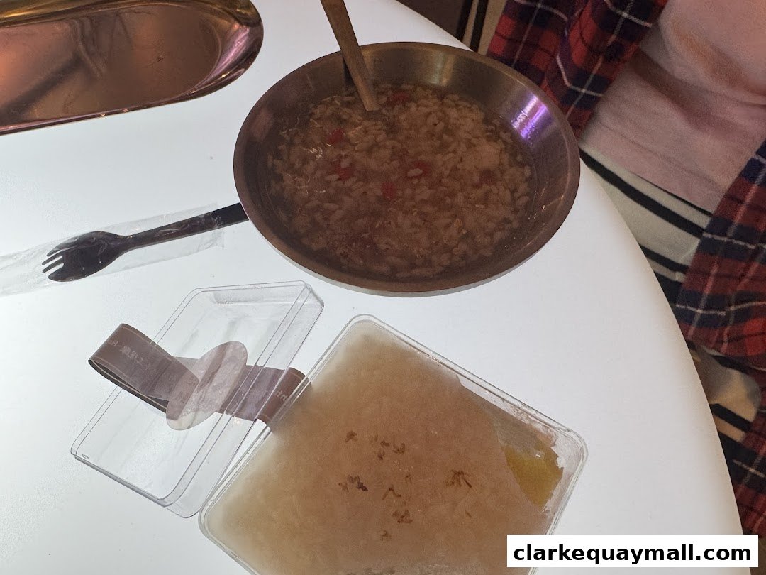 A close-up of fermented rice and a dessert in clear containers on a white table.