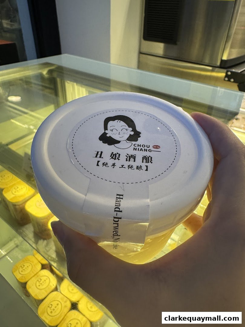 A hand holds a container of fermented rice with a cartoon girl logo.