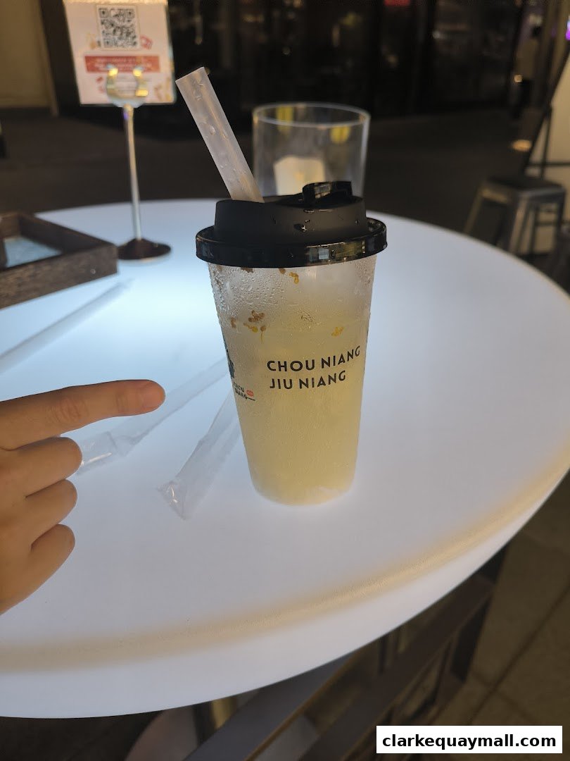 A refreshing drink from Chou Niang Fermented Rice with a straw on a white table.