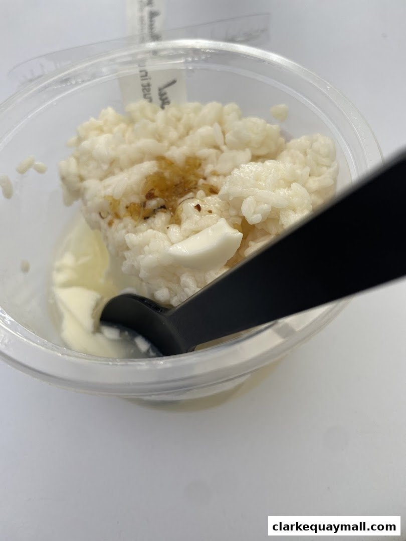A close-up of a dessert in a clear plastic cup with a black spoon.