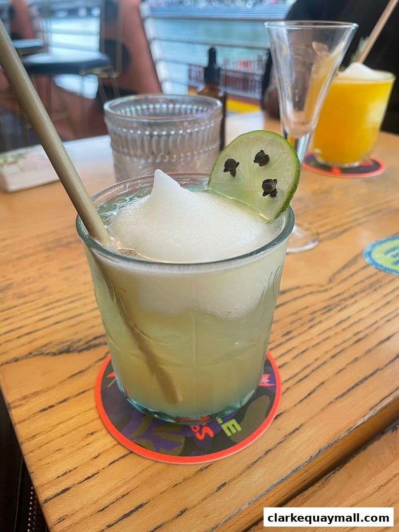 A refreshing frozen cocktail with a lime garnish and a straw on a wooden table.