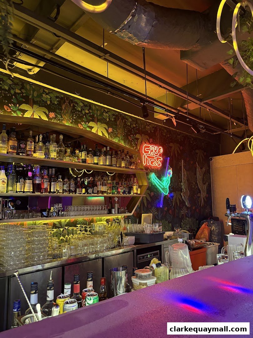 A well-stocked bar with bottles, glassware, and neon signage.