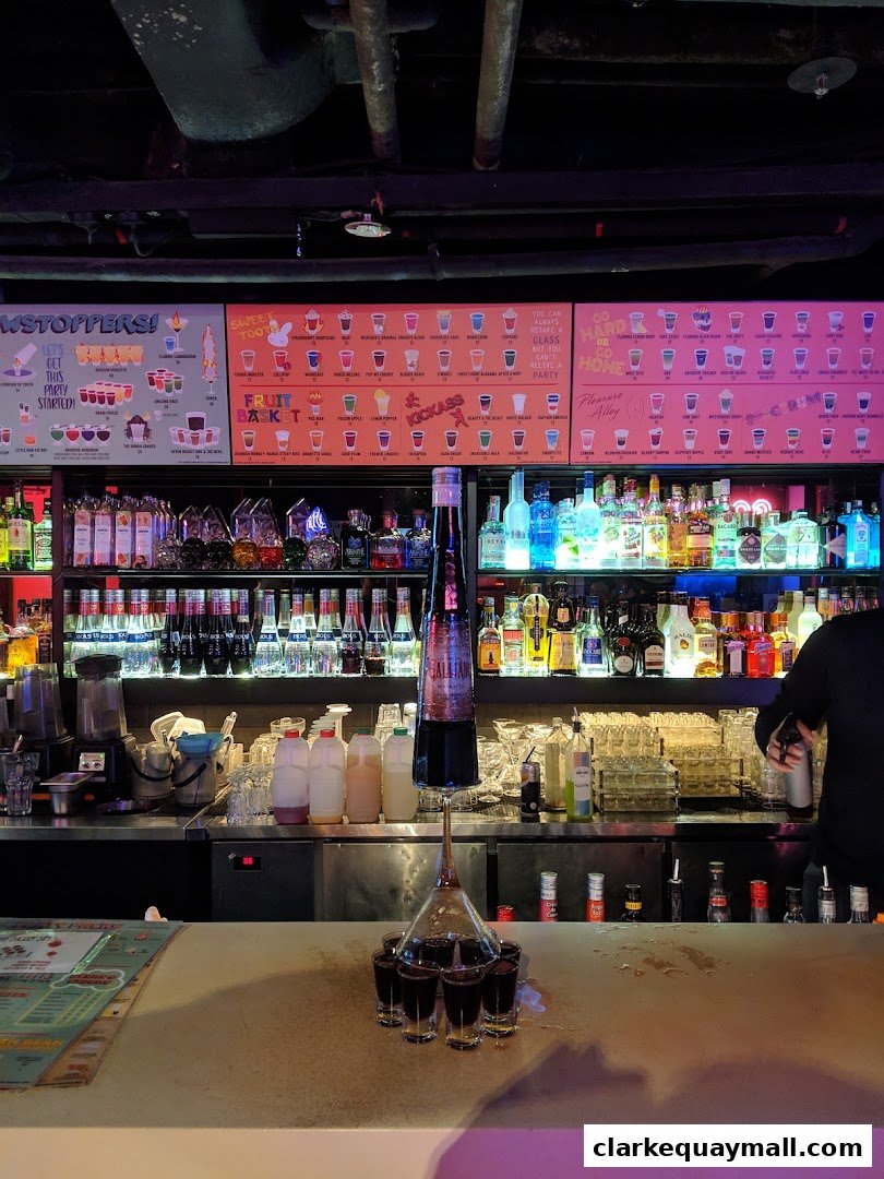 A bar counter with various bottles of alcohol and a display of shots.