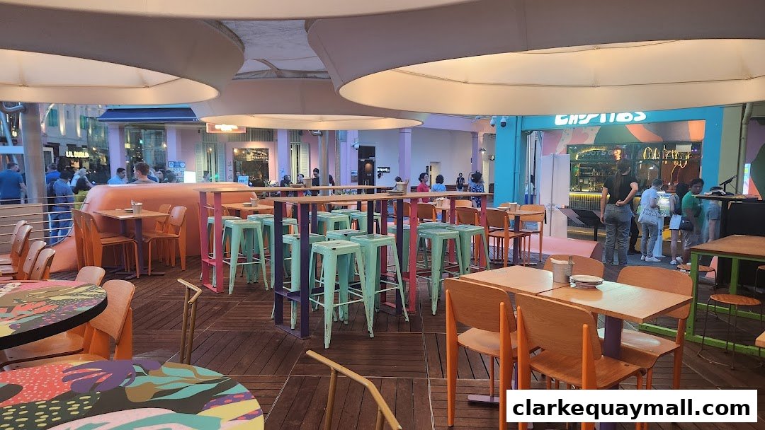 An outdoor seating area with colorful tables and stools, and people in the background.