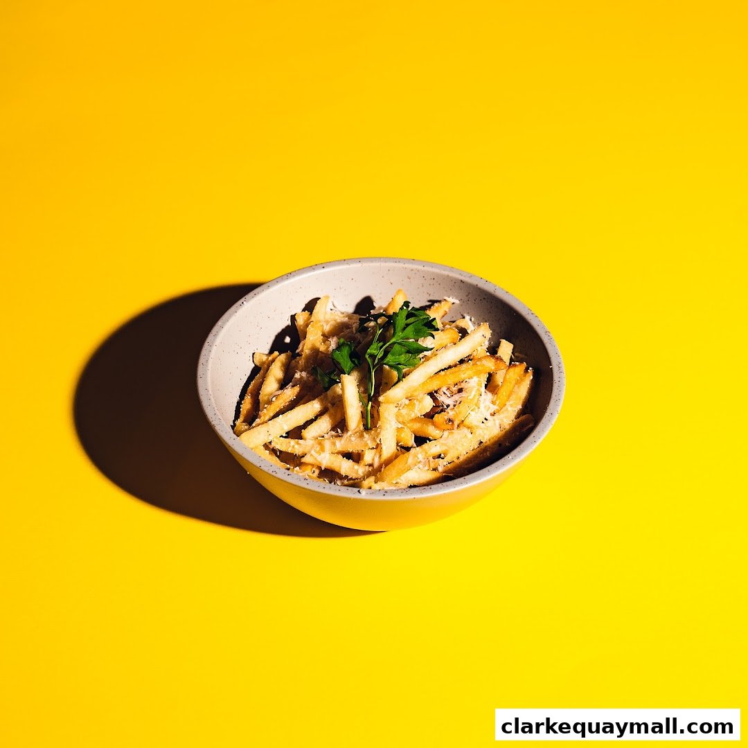 A bowl of french fries topped with cheese and parsley on a yellow background.