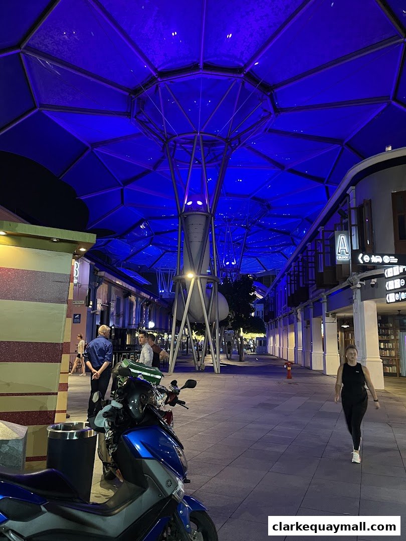 A street scene at night with a blue illuminated canopy and people walking.
