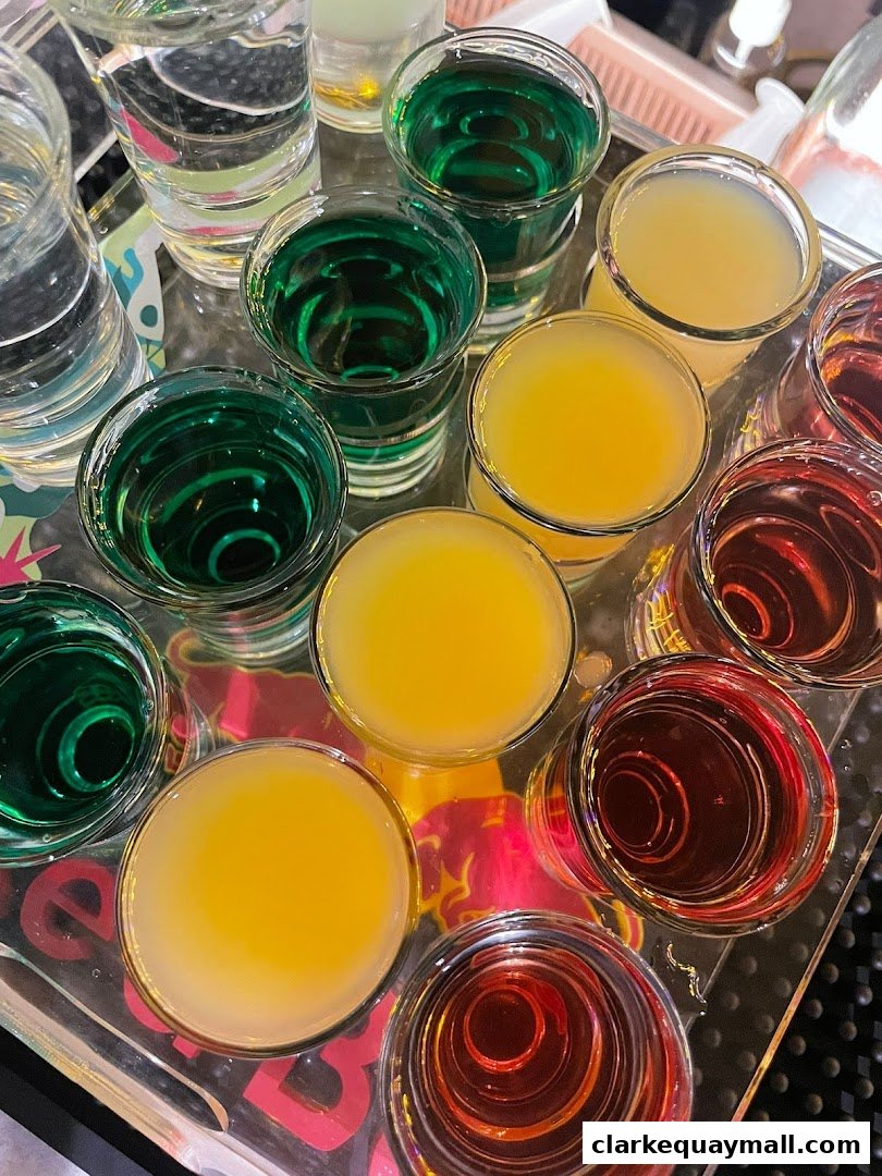 A tray filled with colorful shots of alcoholic beverages, including green, yellow, and red liquids.
