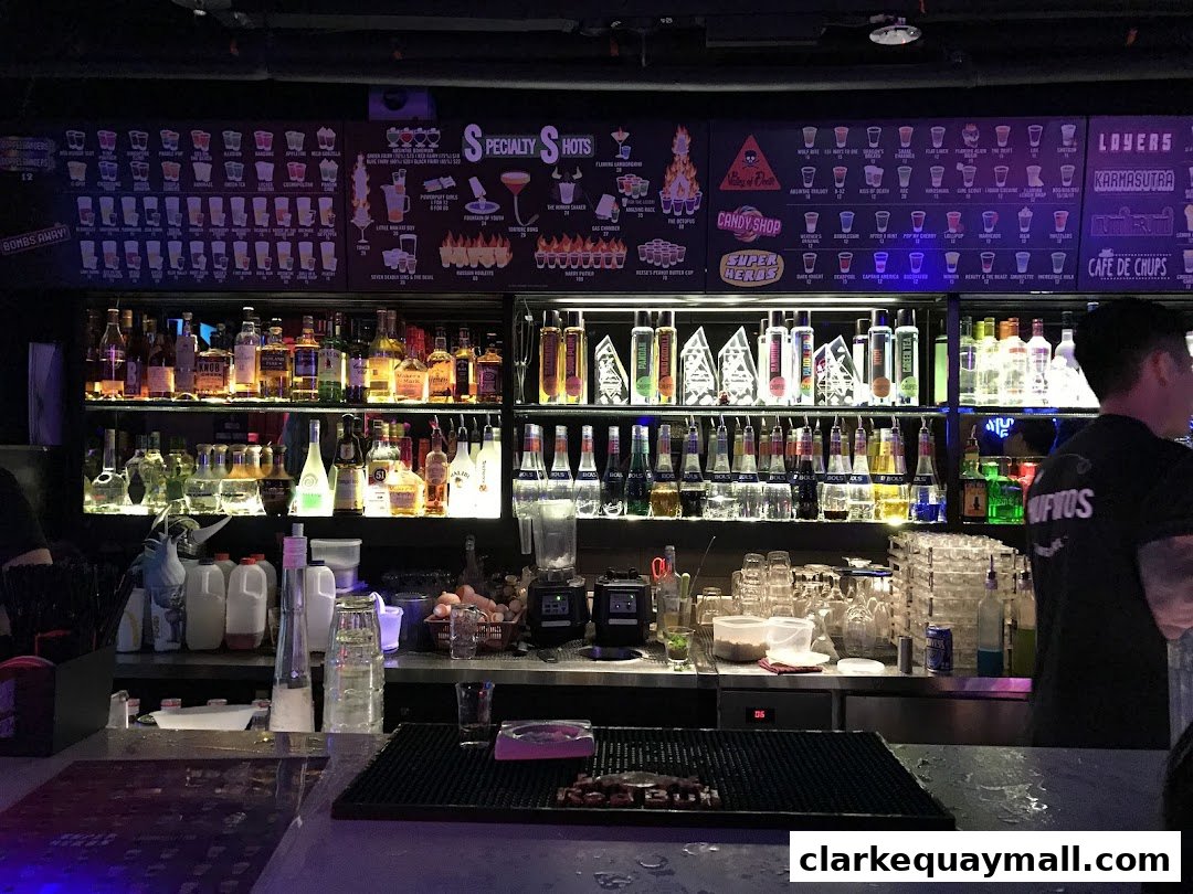 A well-stocked bar with shelves of liquor bottles and a menu board displaying various shots.