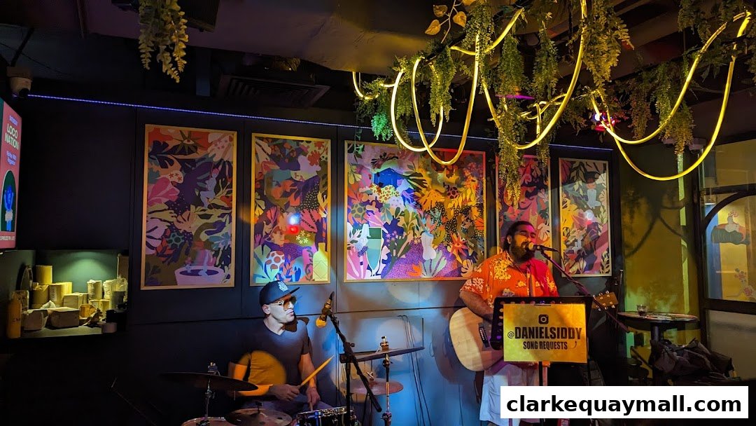 A live band performs in a bar with colorful artwork and hanging plants.