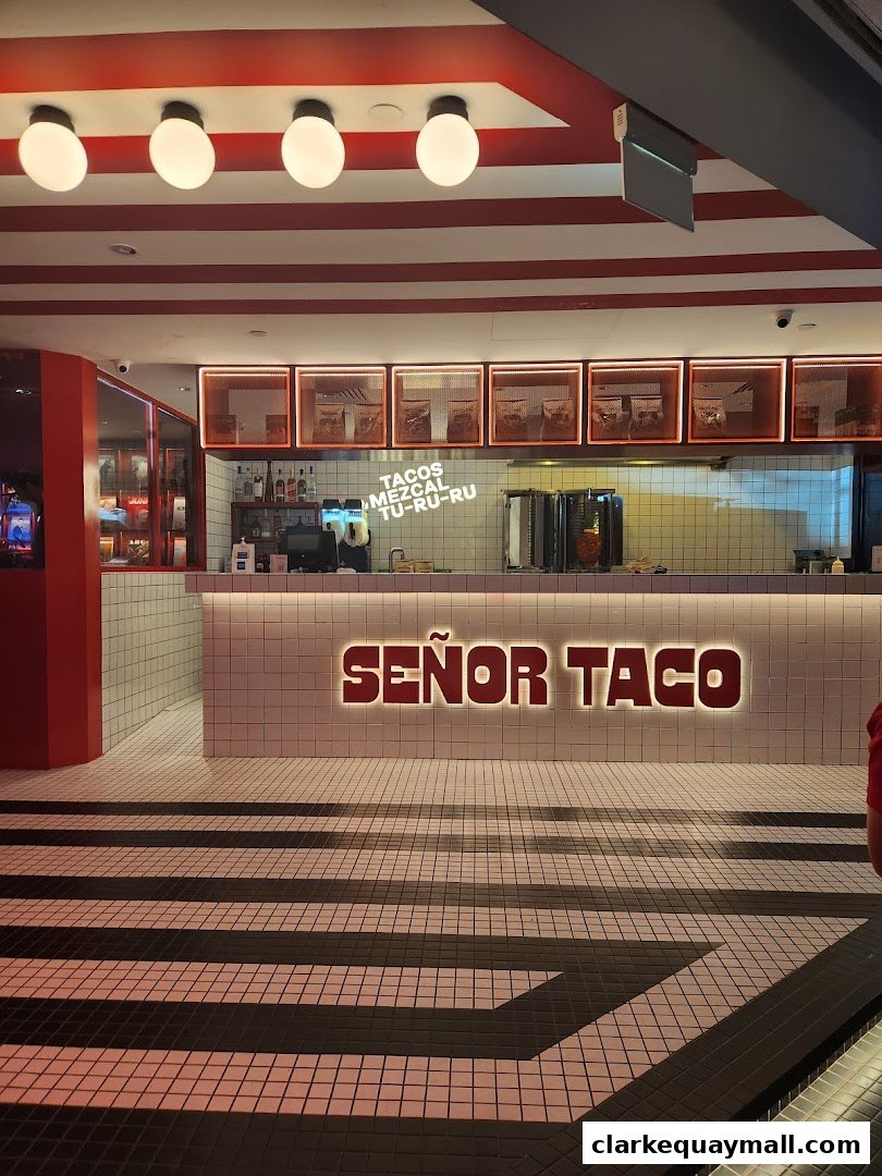 The interior of a modern taco restaurant with a prominent illuminated sign.