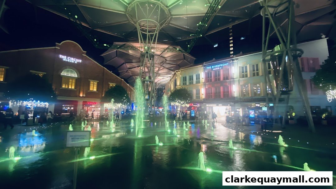 A lively night scene with illuminated fountains and shops at Clarke Quay.