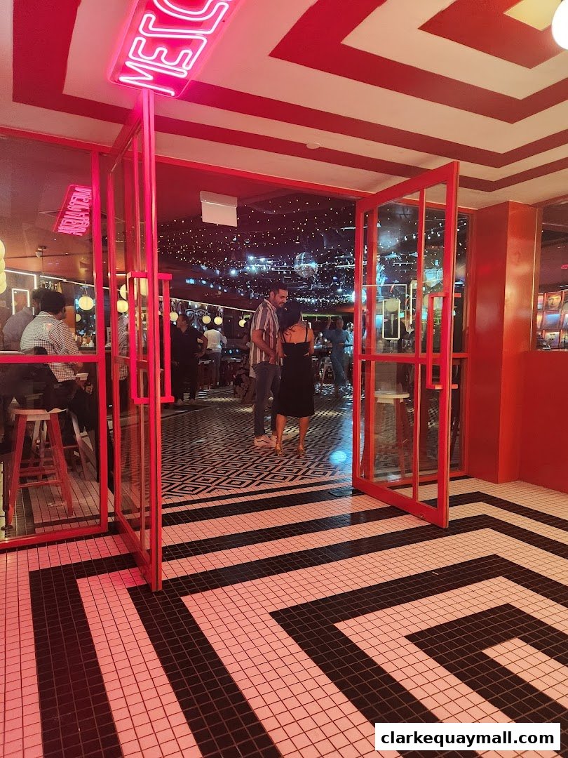 Entrance to a vibrant venue with neon signs, striking geometric flooring, and a lively atmosphere.