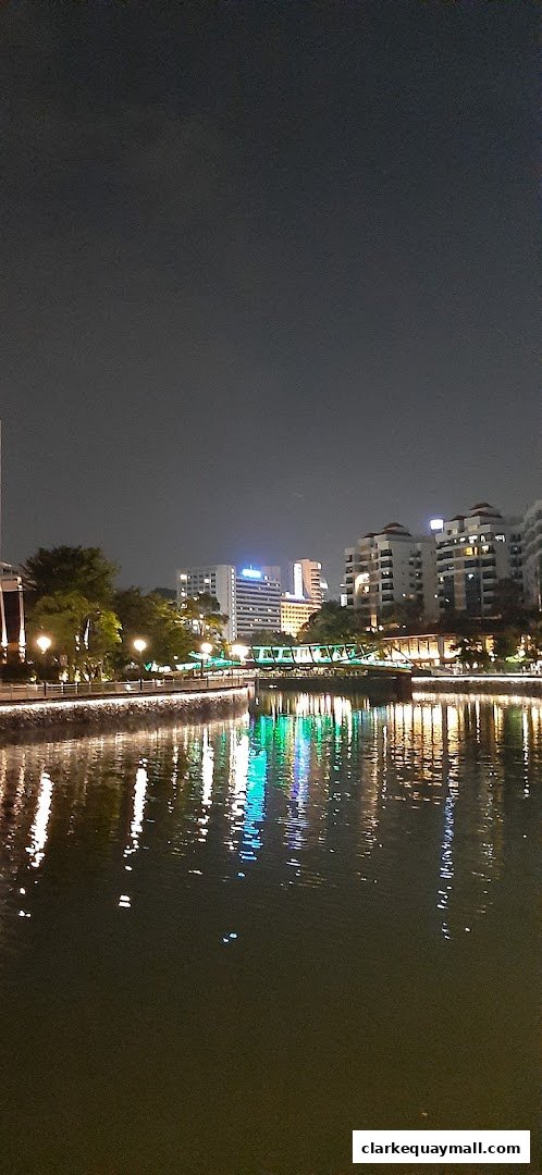 Night view of a river with illuminated buildings and a bridge reflecting on the water.