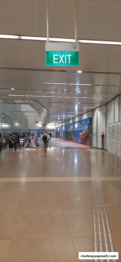 A person walks down a brightly lit corridor with an illuminated EXIT sign overhead.