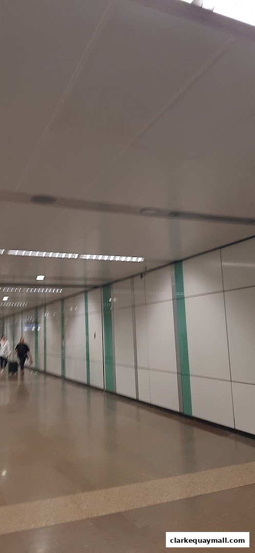 People walking down a modern, well-lit corridor with white walls and green accents.