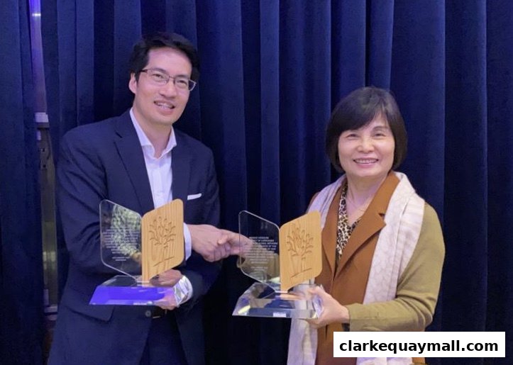 Two people, a man and a woman, are holding awards with a tree logo.