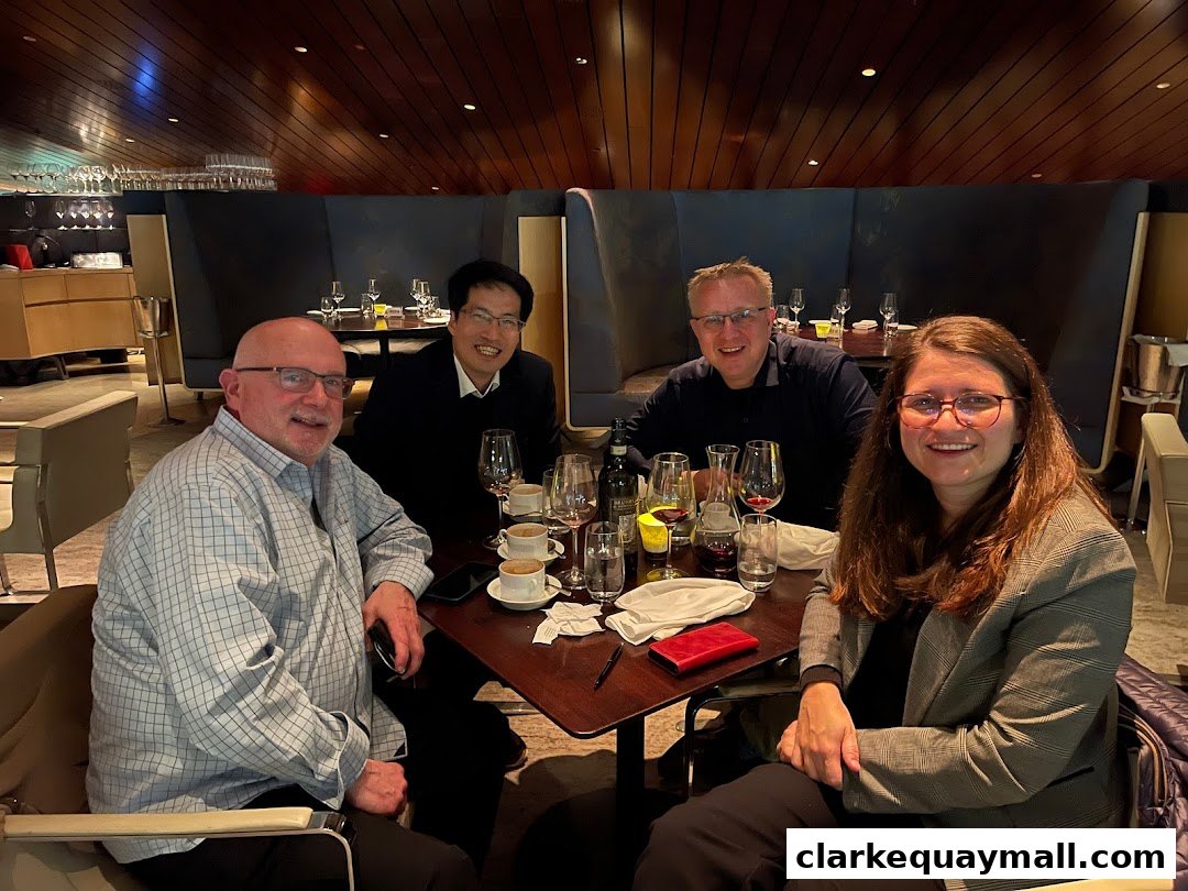 Four people are seated at a table in a restaurant, smiling at the camera.