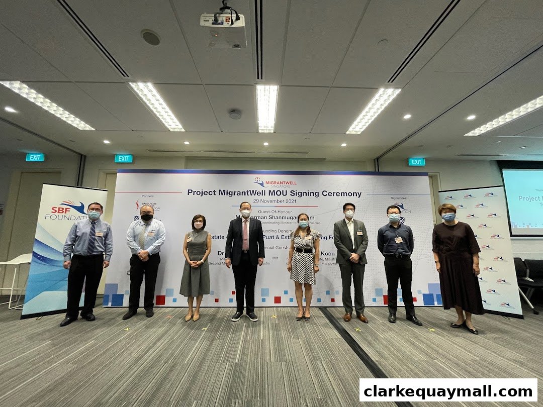 A group of people stand for a photo at the Project MigrantWell MOU Signing Ceremony.