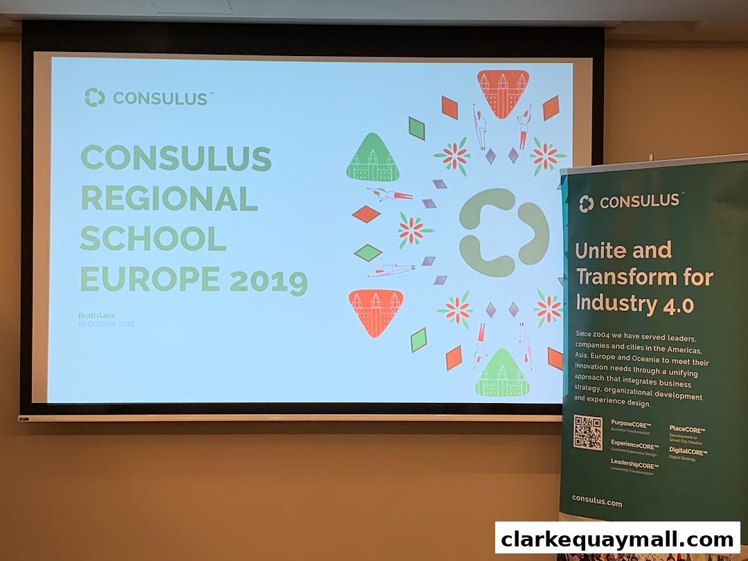 A presentation screen displays "Consulus Regional School Europe 2019" next to a banner about Industry 4.0.