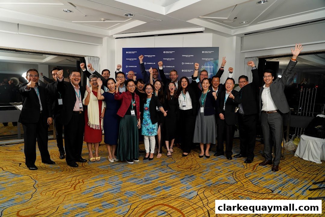 A group of people in business attire are celebrating with raised arms in front of a backdrop.