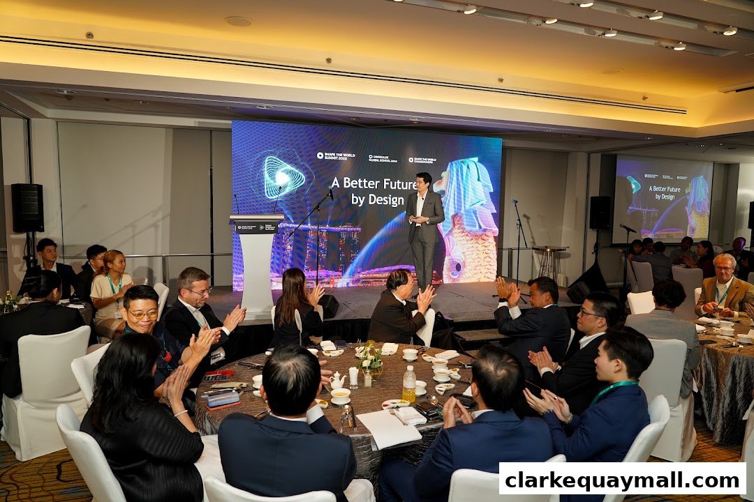 A speaker presents on stage at an event with an audience clapping.