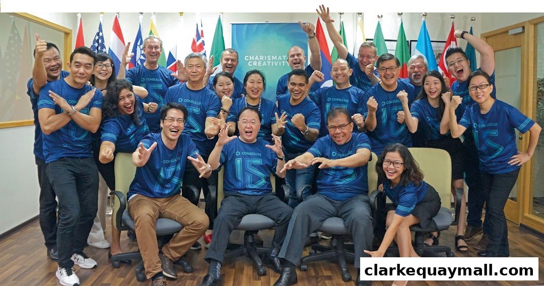 A diverse group of people in blue t-shirts with the Consulus logo, posing enthusiastically.