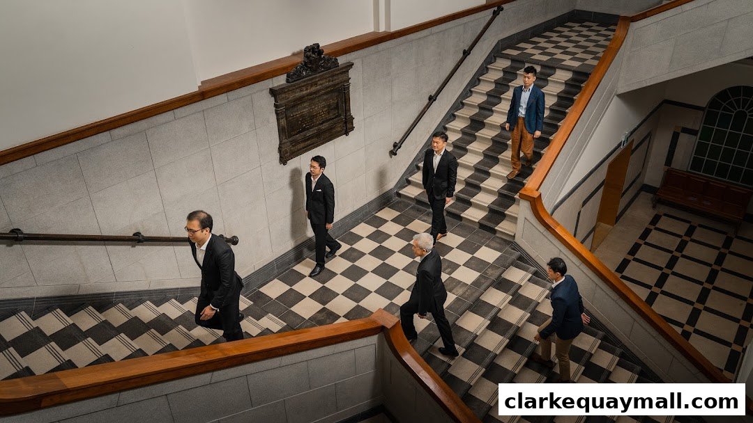 Several men in suits walk up a grand staircase with a checkered pattern.