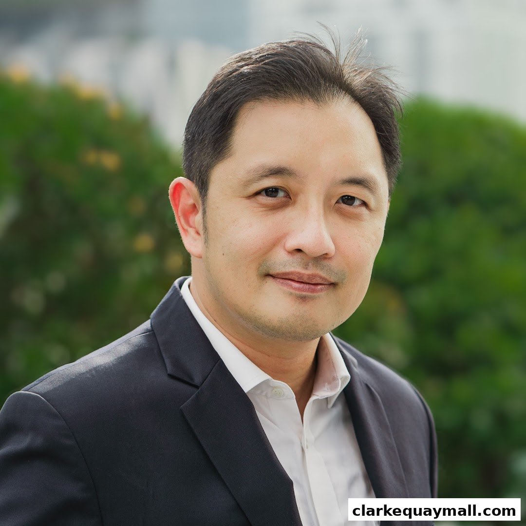 A professional headshot of a man in a suit and white shirt against a blurred green background.