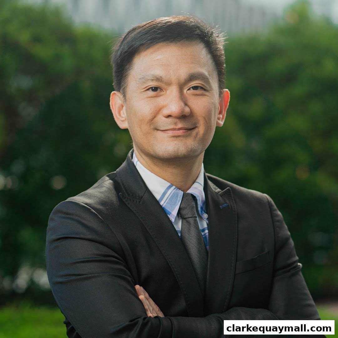 A professional portrait of a man in a suit with his arms crossed.