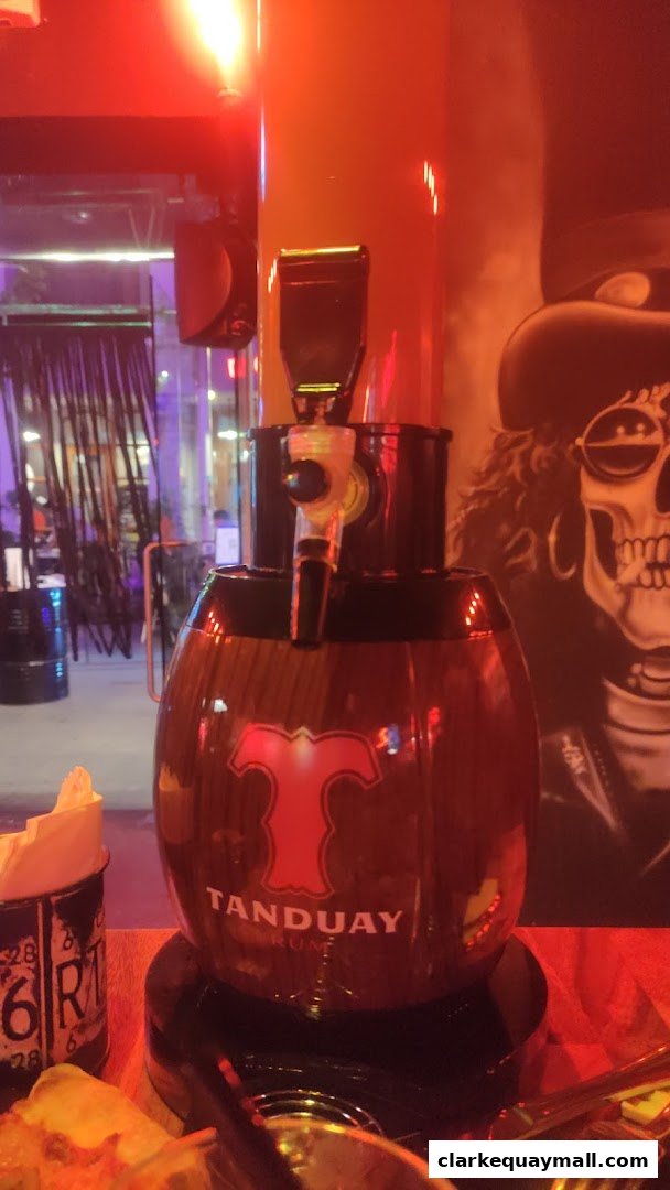 A Tanduay Rum dispenser with a skull graphic in the background at Coyote Ugly Saloon.