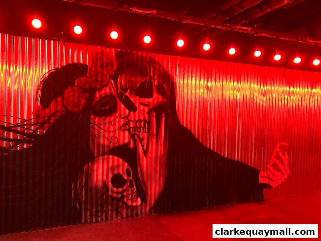 A striking mural of skulls and a woman with floral headdress under red lighting.