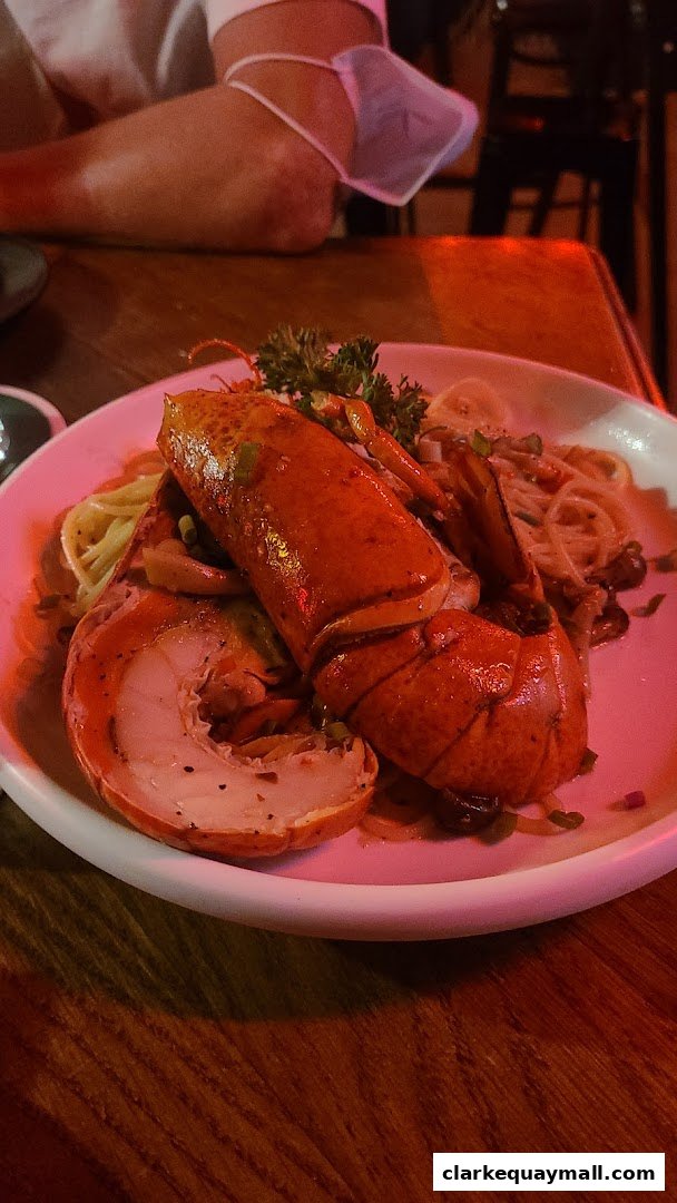 A close-up of a lobster pasta dish served on a white plate at a restaurant.