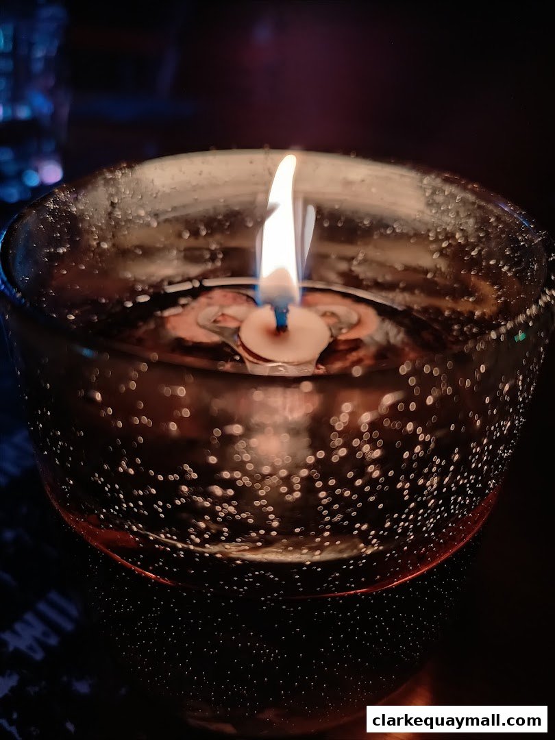 A close-up shot of a lit candle in a glass bowl with water and bubbles.