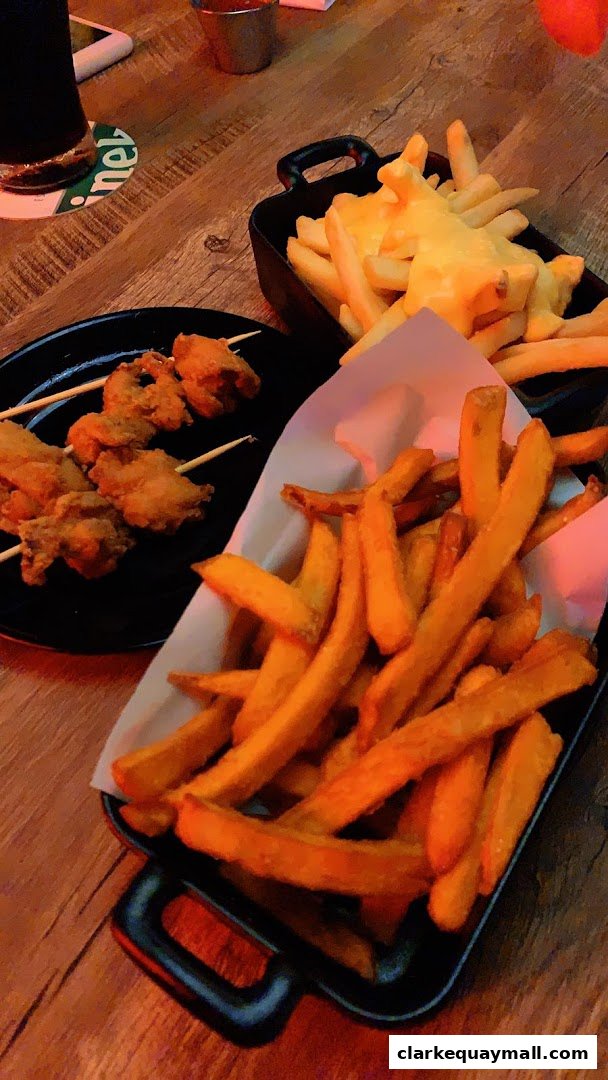 A close-up shot of fried chicken skewers and french fries served on a wooden table.